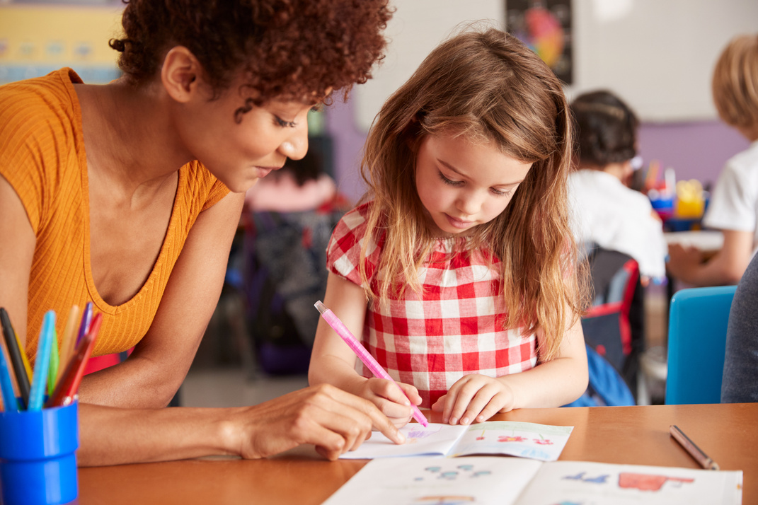 Elementary School Teacher Giving Female Pupil One to One Support